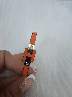 Eleganter Damen-Armreif in Goldoptik mit orangefarbenen Details  