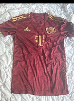 bordeauxfarbene FC Bayern München Wiesn-Trikot 2022 von Adidas mit eleganten goldenen Details.