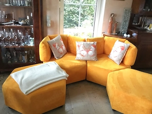 Modulares Sofa in warmen Gelb mit zwei Hockern
